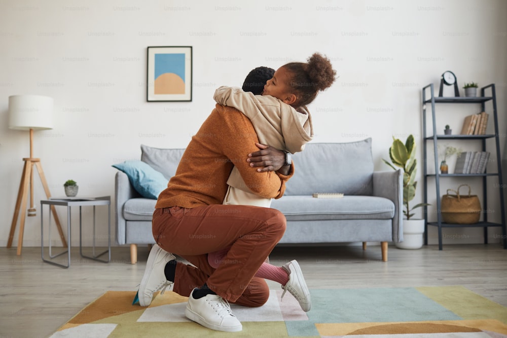 Side view portrait of happy father embracing little girl after coming home from work on Fathers day, copy space