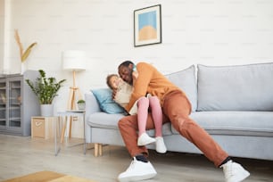 Retrato de cuerpo entero de un feliz padre afroamericano abrazando a su hija después de llegar a casa del trabajo el día del padre, espacio de copia