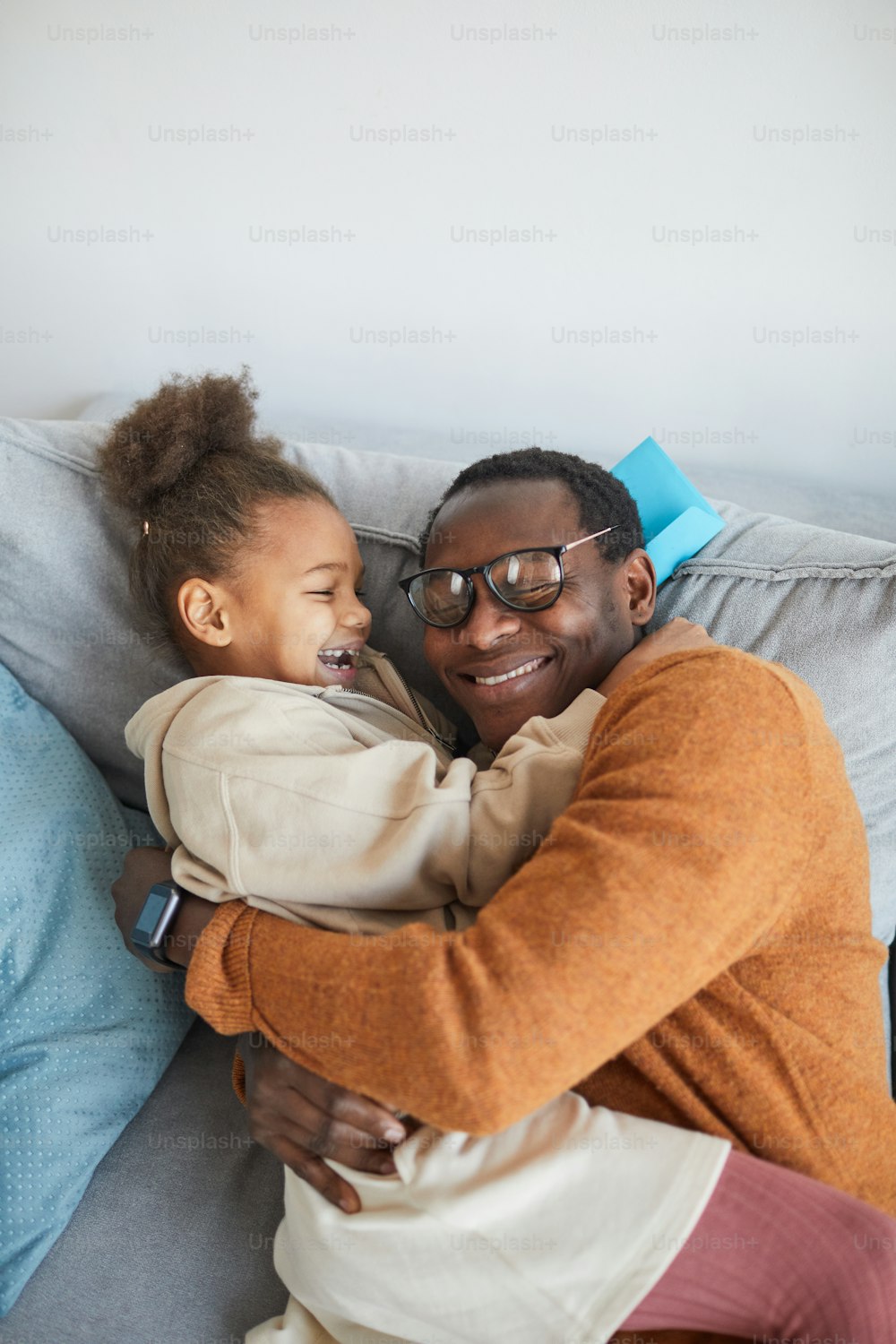 Retrato de alto ángulo de un feliz padre afroamericano abrazando a su hija después de llegar a casa del trabajo el día del padre