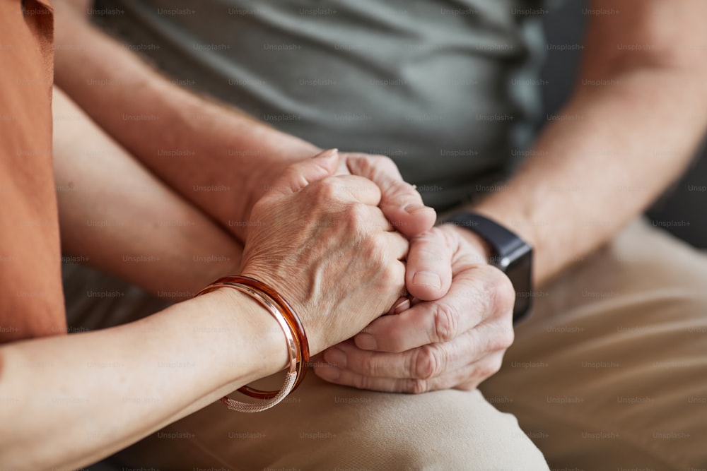 Close up de casal idoso atencioso de mãos dadas e apoiando um ao outro com amor