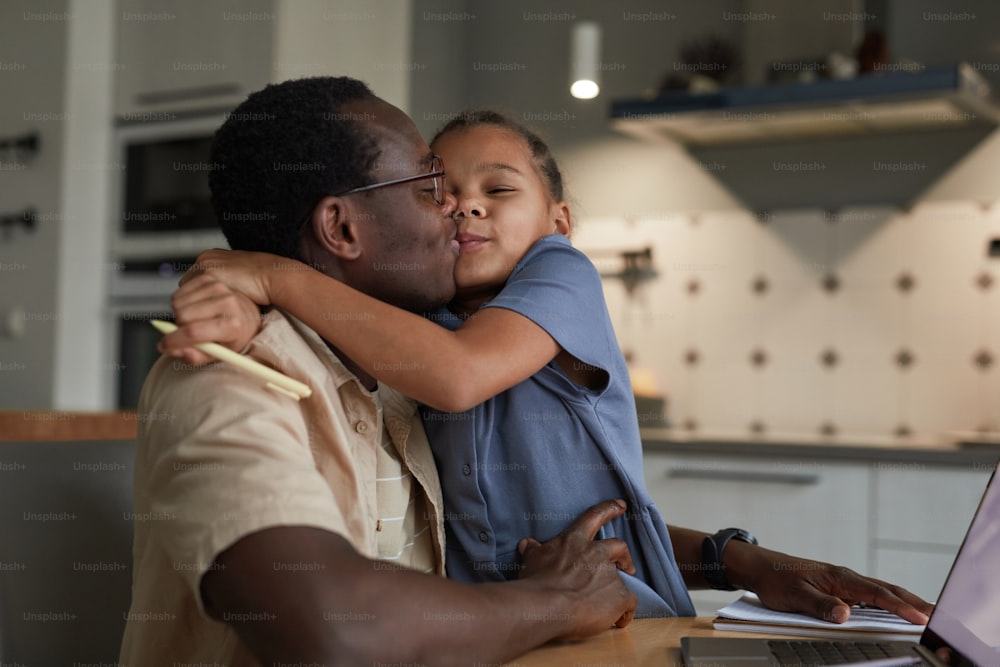 Cute family scene of caring black father kissing daughter with love in home interior