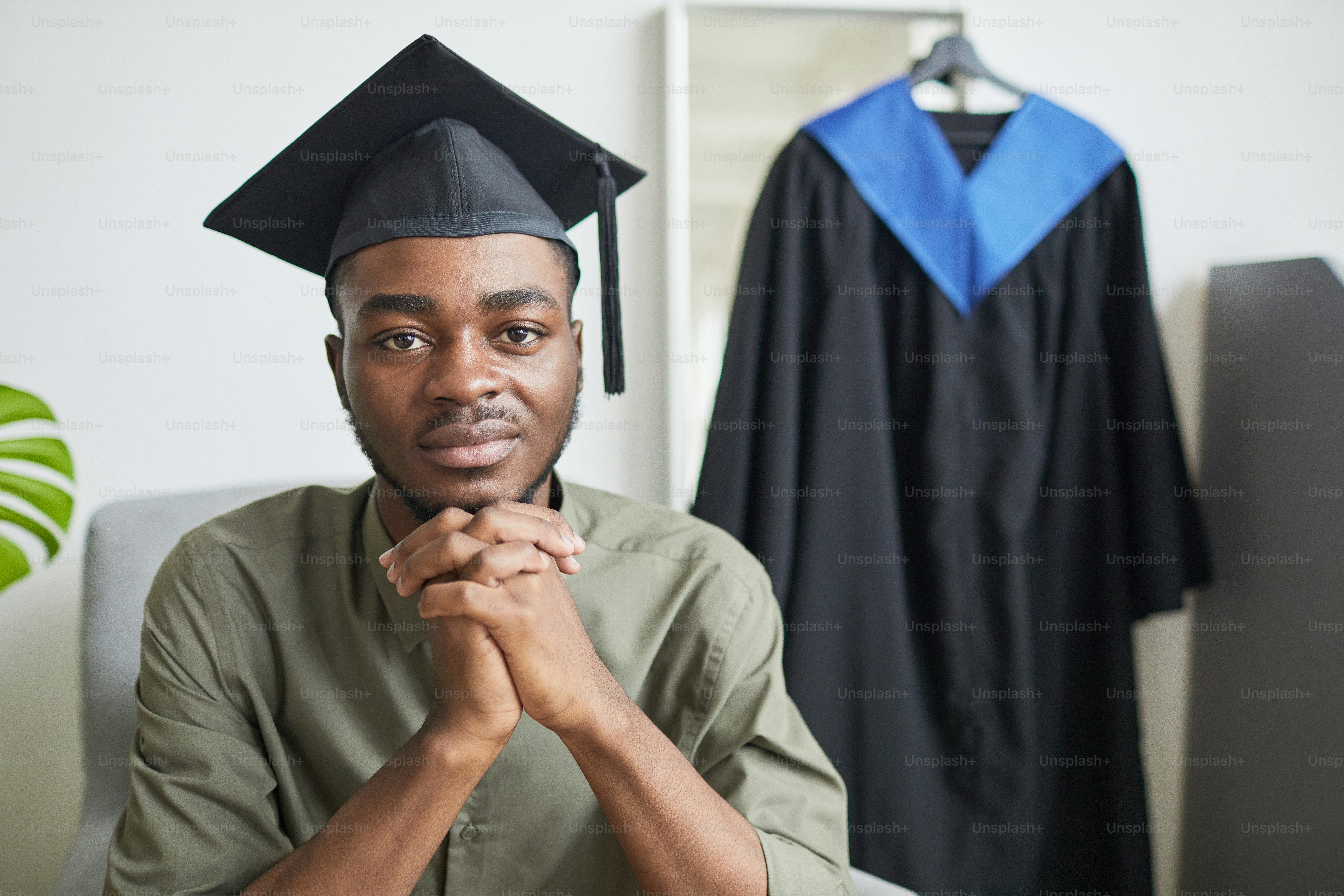 Portrait of young African-American man looking at camera while preparing for graduation ceremony indoors