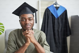 Portrait d’un jeune homme afro-américain regardant la caméra alors qu’il se prépare pour la cérémonie de remise des diplômes à l’intérieur