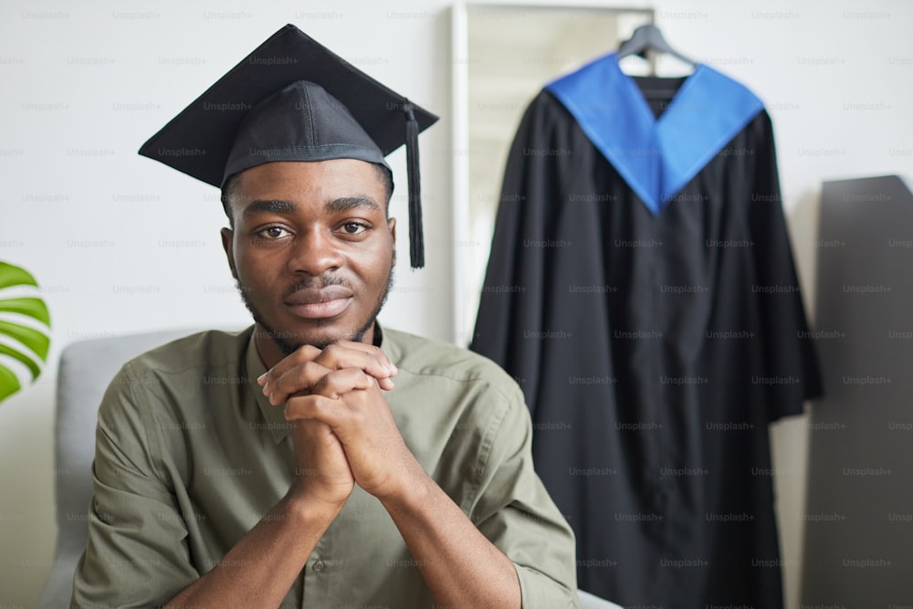 Ritratto di giovane afroamericano che guarda la macchina fotografica mentre si prepara per la cerimonia di laurea al chiuso