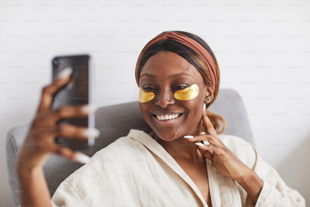 Portrait minimal d’une belle femme afro-américaine appréciant la routine de soins de la peau à la maison et parlant par chat vidéo, espace de copie
