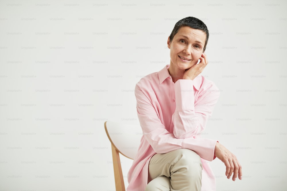 Minimal portrait of confident mature businesswoman looking at camera while wearing pink shirt, copy space