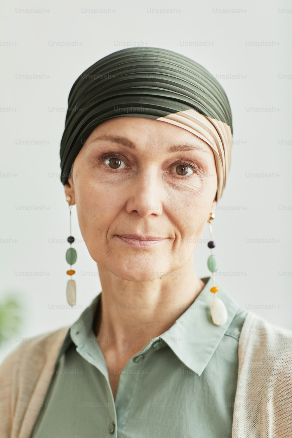 Vertical closeup portrait of mature woman wearing headscarf and looking at camera calmly