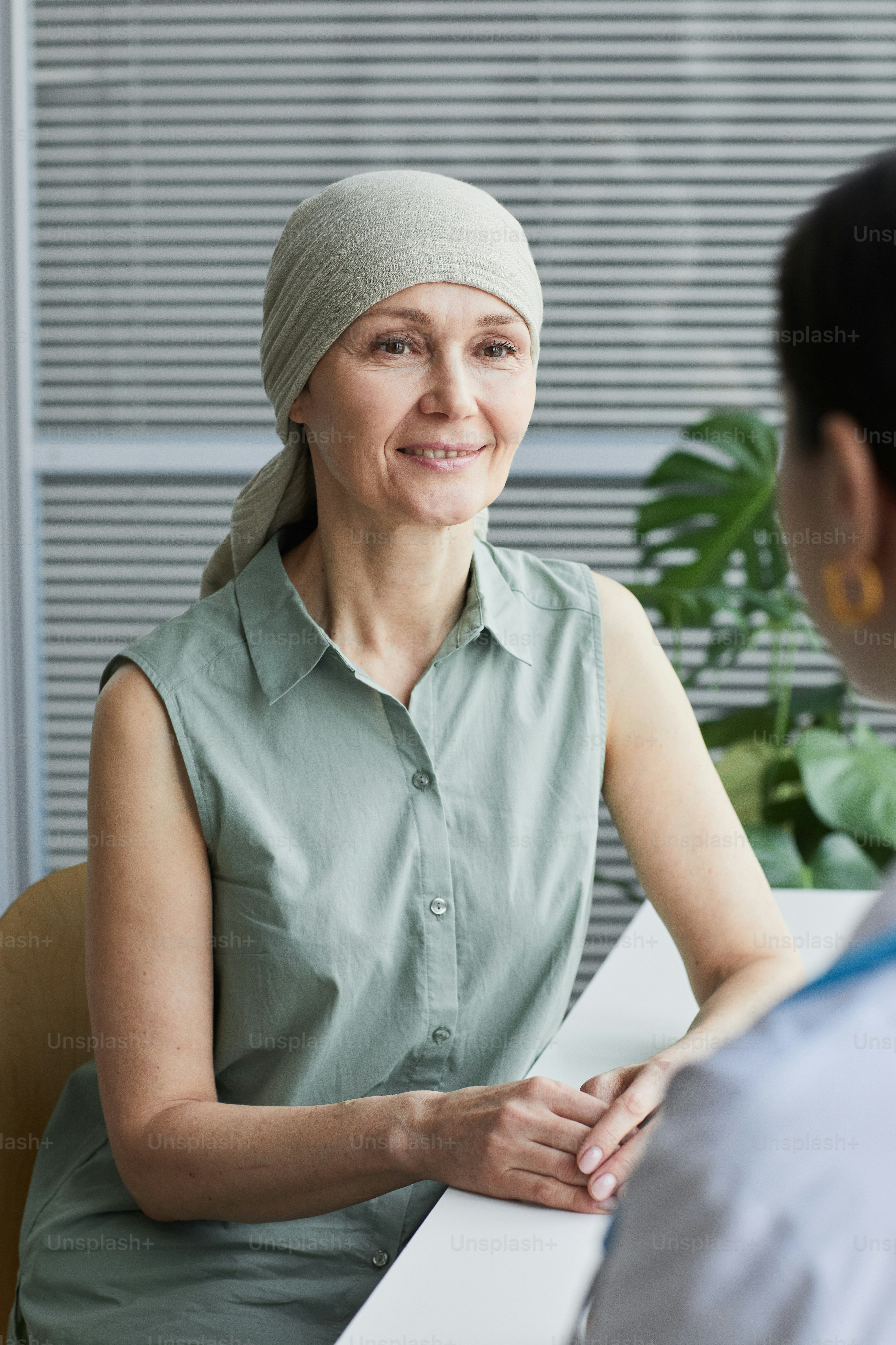 Vertical portrait of smiling mature woman talking to female doctor during consultation in medical clinic
