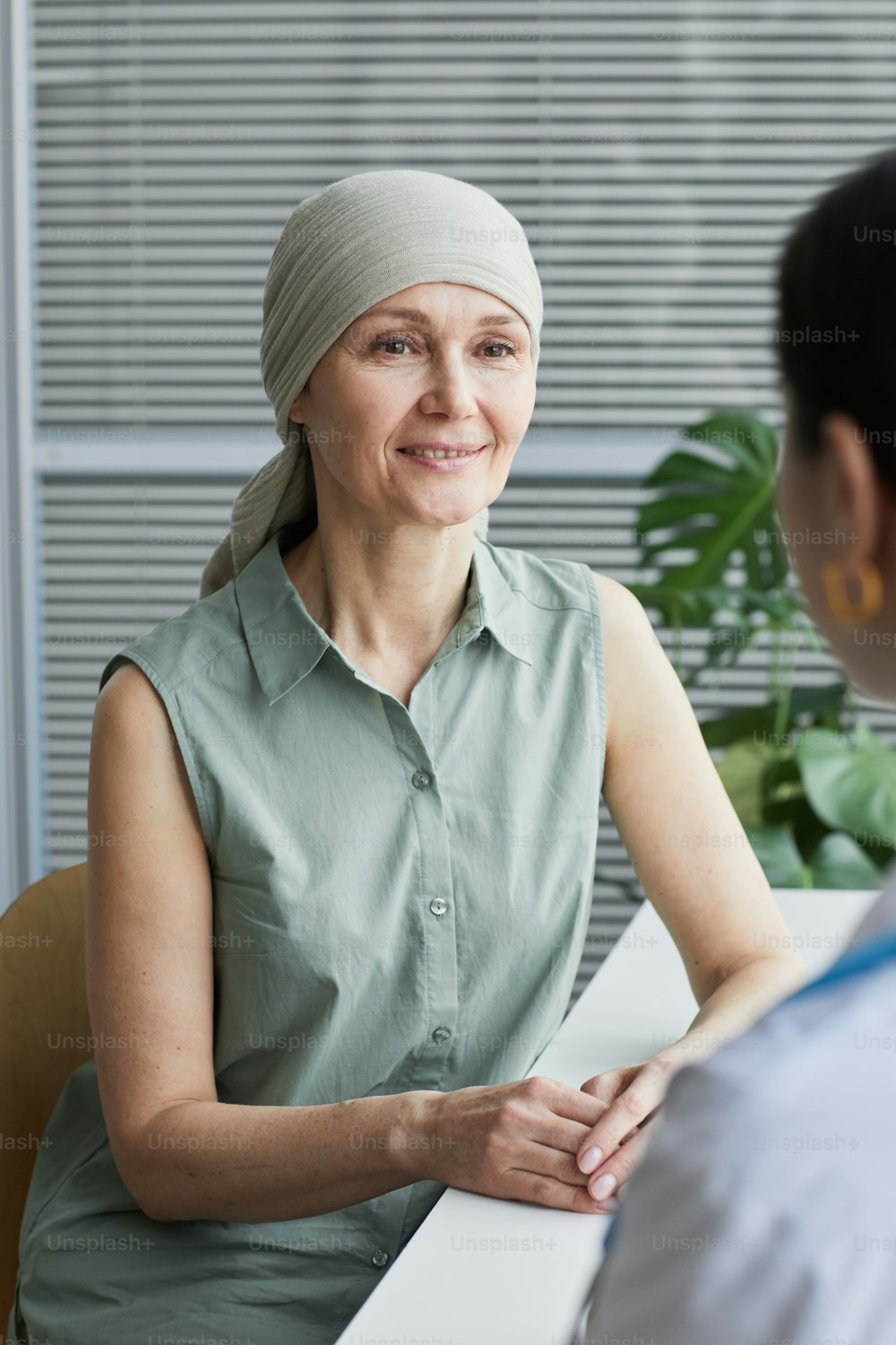 Vertical portrait of smiling mature woman talking to female doctor during consultation in medical clinic