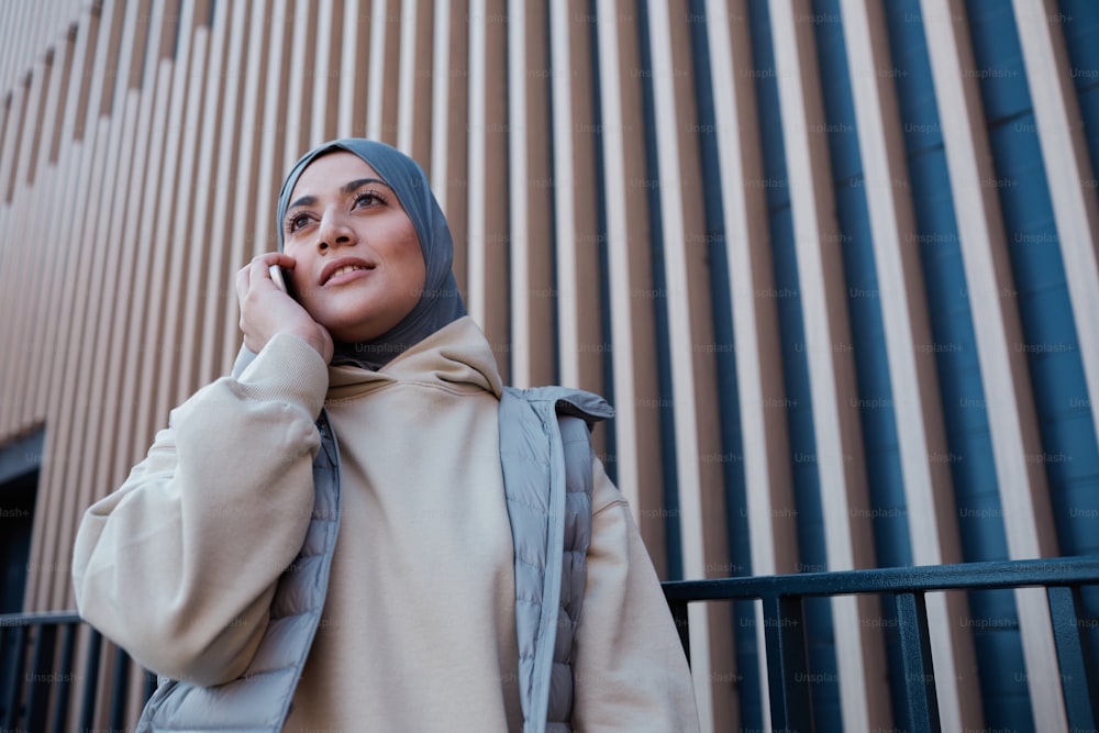 Retrato gráfico de cintura para arriba de una mujer moderna de Oriente Medio hablando por teléfono inteligente en la ciudad, espacio de copia