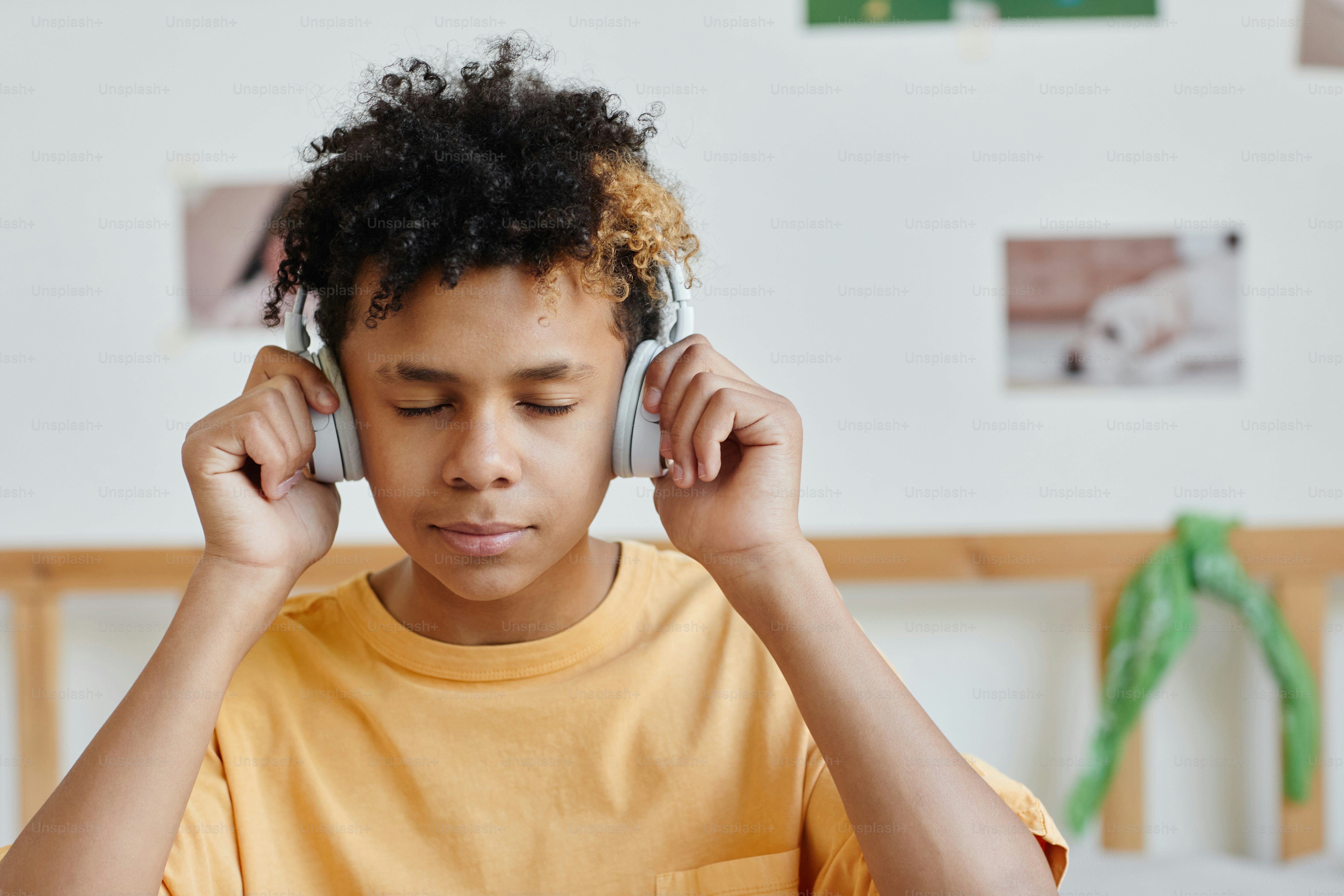 Portrait of mixed-race teenage boy wearing headphones and listening to music with eyes closed, copy space