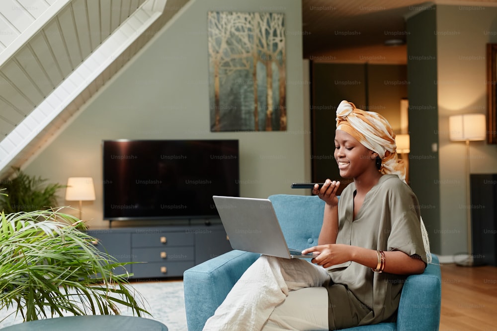 Portrait of smiling African-American businesswoman working at home and using laptop, copy space