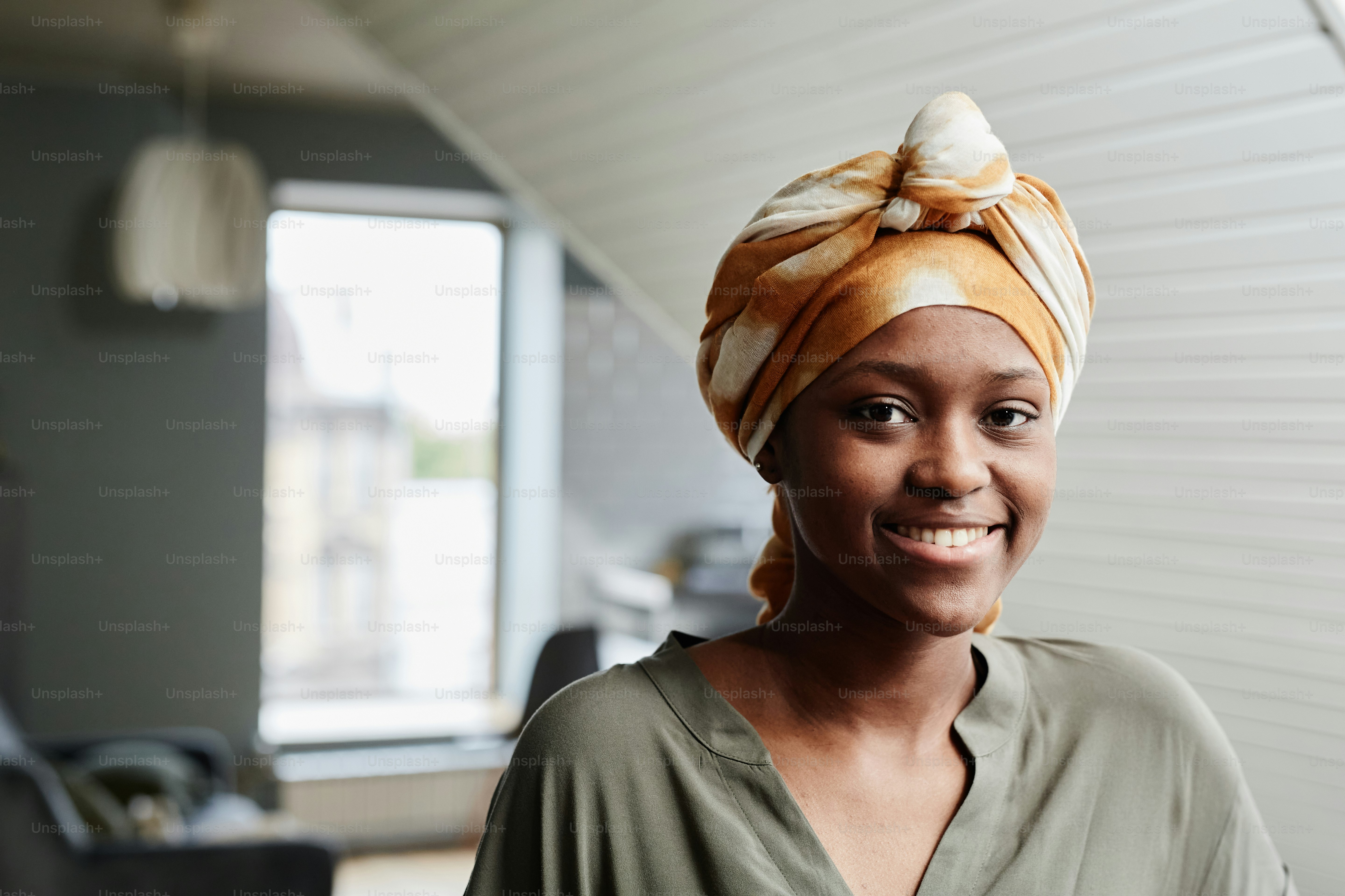 Portrait of young African-American woman smiling at camera in home interior, copy space