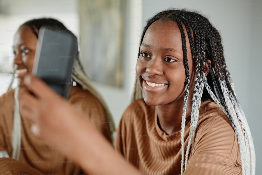 Portrait of young African-American woman video chatting with friends via smartphone and smiling