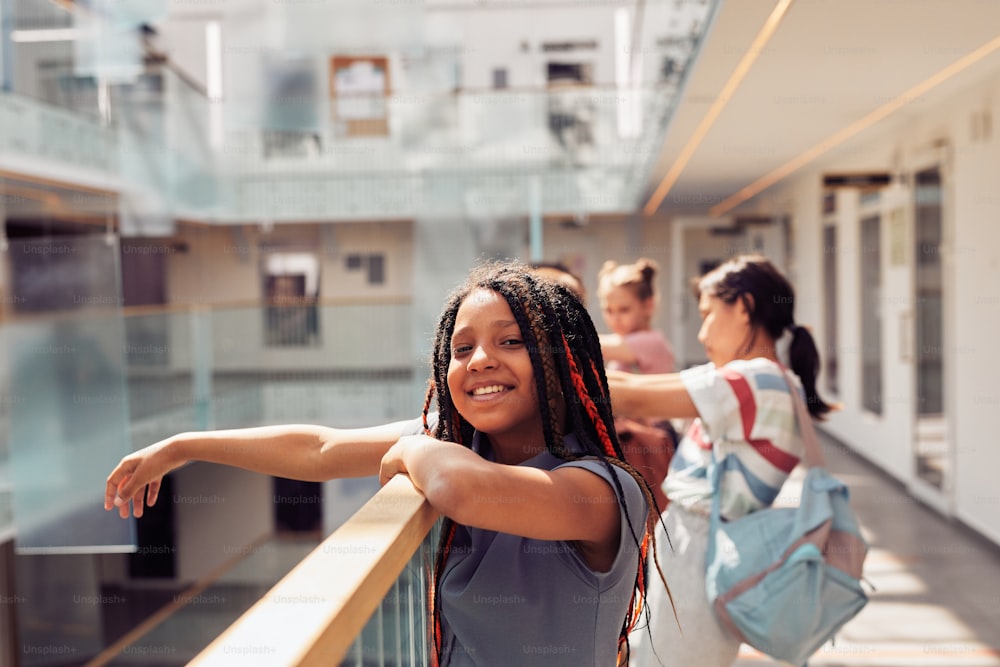 Portrait of smiling African-American girl enjoying first day at school and looking at camera while standing in sunlight, copy space