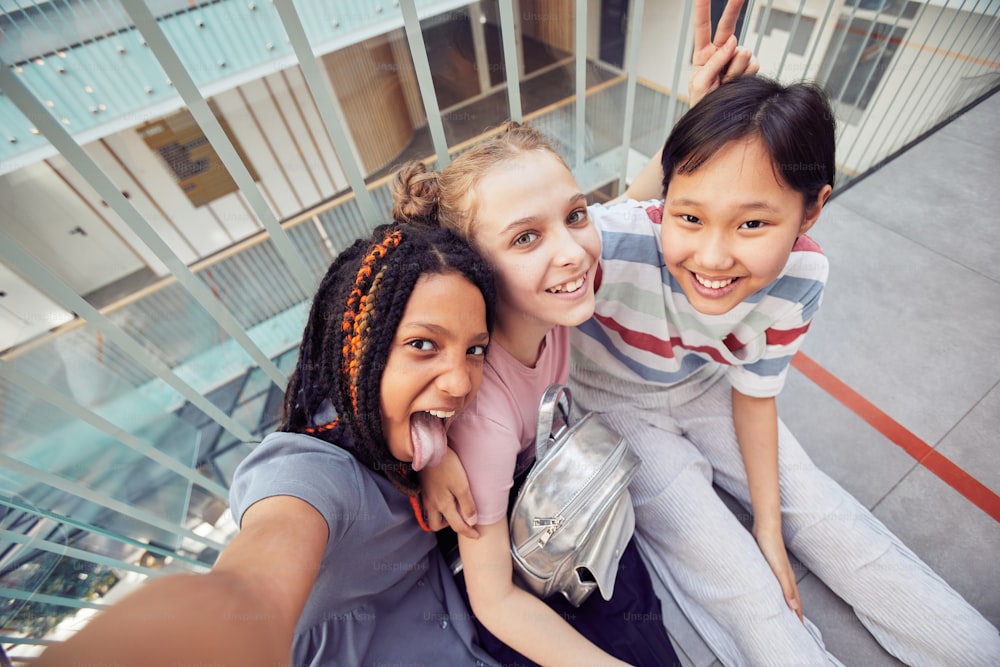 POV high angle view at diverse group of schoolgirls taking selfie together