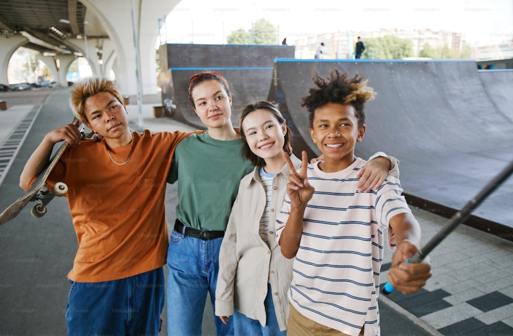Foto vibrante de um grupo diversificado de adolescentes tirando selfie ao ar livre na área urbana e sorrindo para a câmera