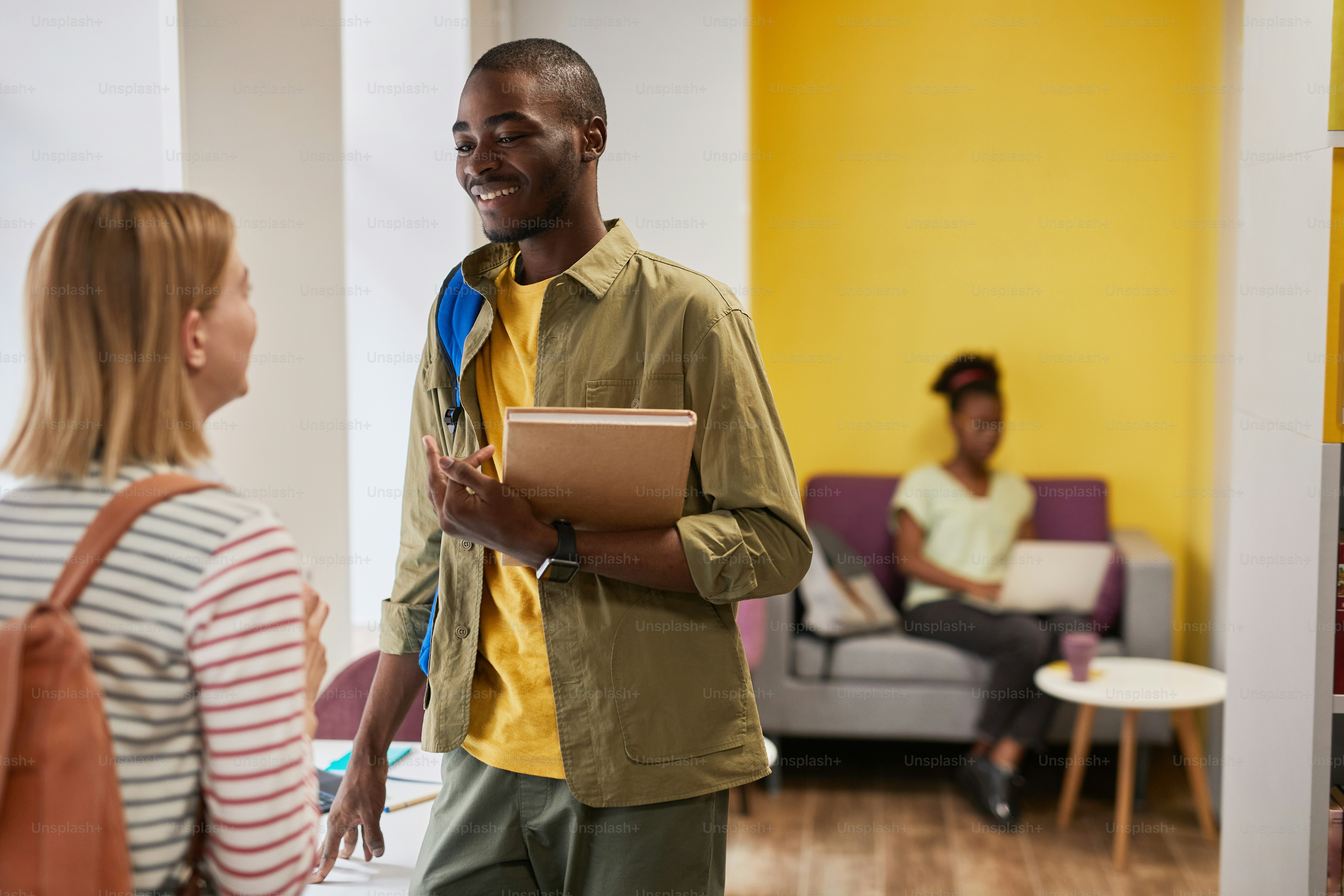 Porträt eines jungen afroamerikanischen Studenten, der sich mit einem Freund auf dem College-Campus unterhält