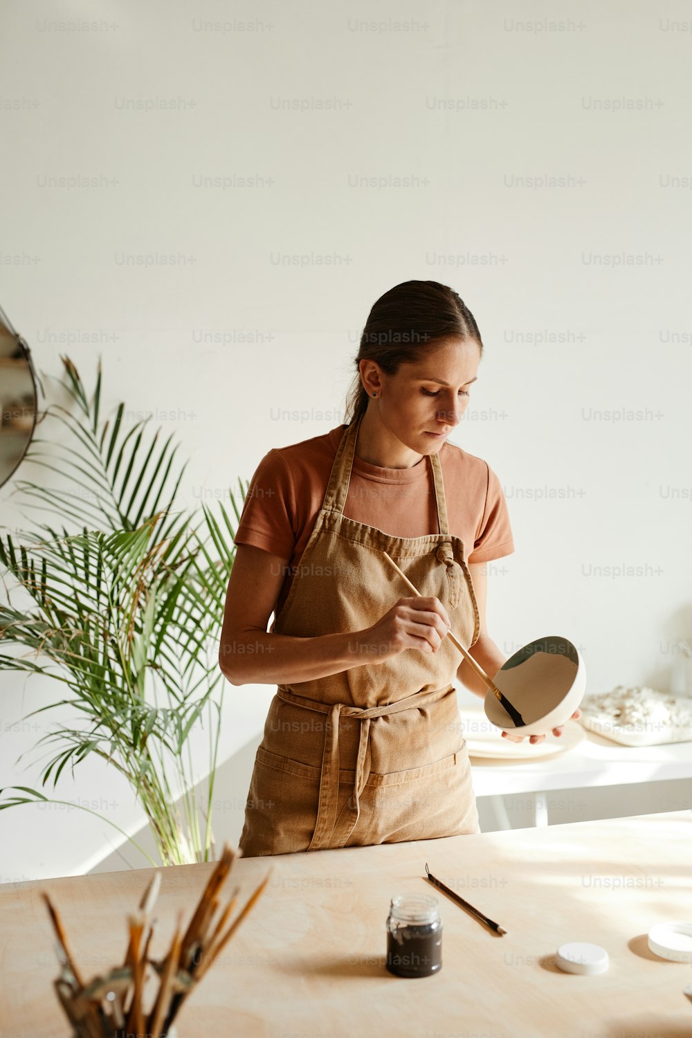 Minimal portrait of young female artist decorating ceramics in pottery workshop, copy space