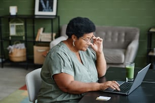 Retrato de vista lateral de una mujer mayor negra que usa una computadora portátil para compras en línea, espacio de copia