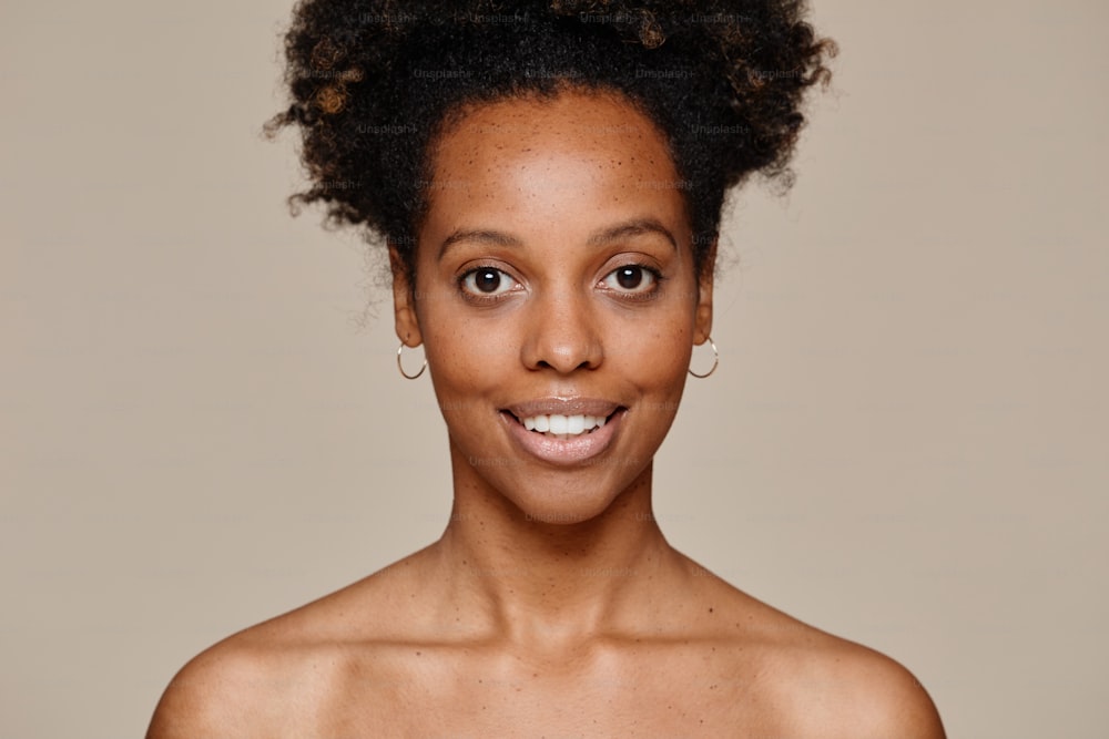 Retrato mínimo de una joven afroamericana sonriendo a la cámara demostrando una hermosa piel natural y una sonrisa de dientes blancos