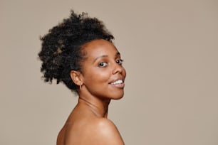 Portrait minimal d’une jeune femme afro-américaine démontrant une belle peau naturelle et des dents blanches sourire, espace de copie
