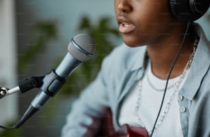 Close up de jovem negra cantando ao microfone e gravando músicas em casa, espaço de cópia