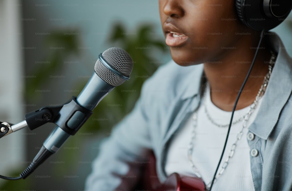 Primer plano de una joven negra cantando al micrófono y grabando canciones en casa, copie el espacio