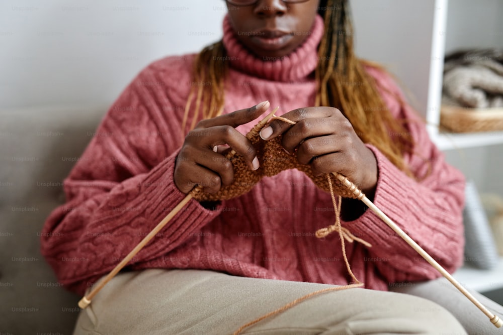 Cropped of young African-American woman knitting while enjoying cozy weekend at home, copy space