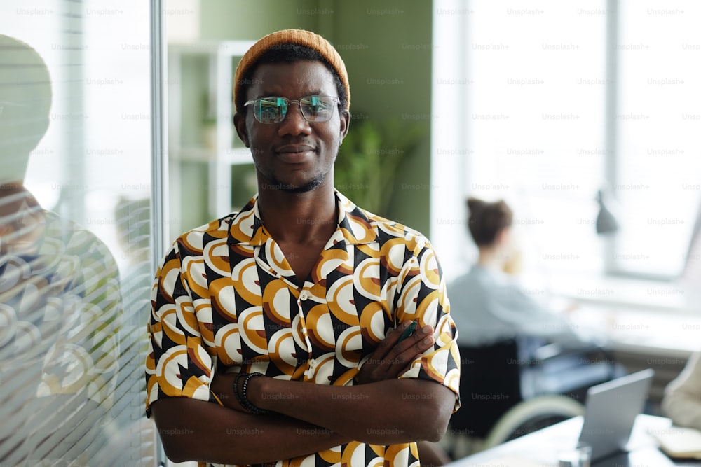 Waist up portrait of black young man wearing bright yellow pattern in office and looking at camera while posing confidently,copy space