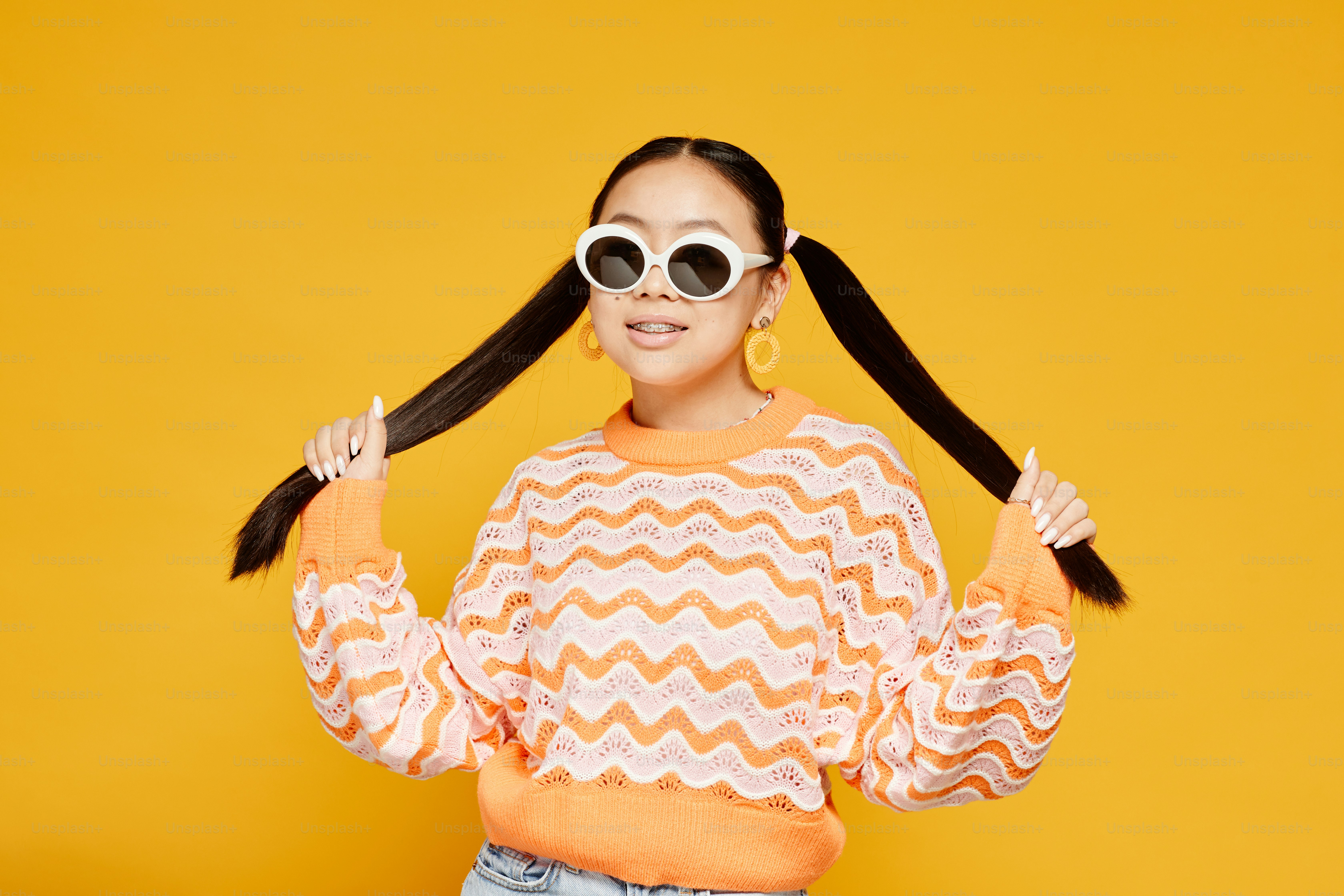Waist up portrait of funky teenage girl with pigtails over colored yellow background, copy space
