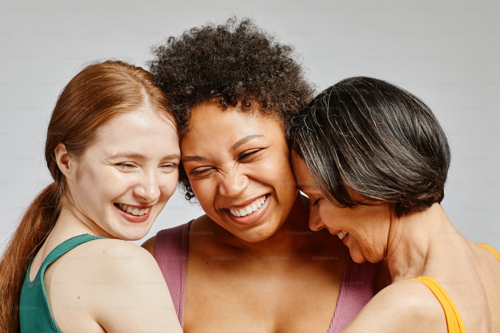 Retrato sincero de tres mujeres jóvenes diversas riendo felices juntas