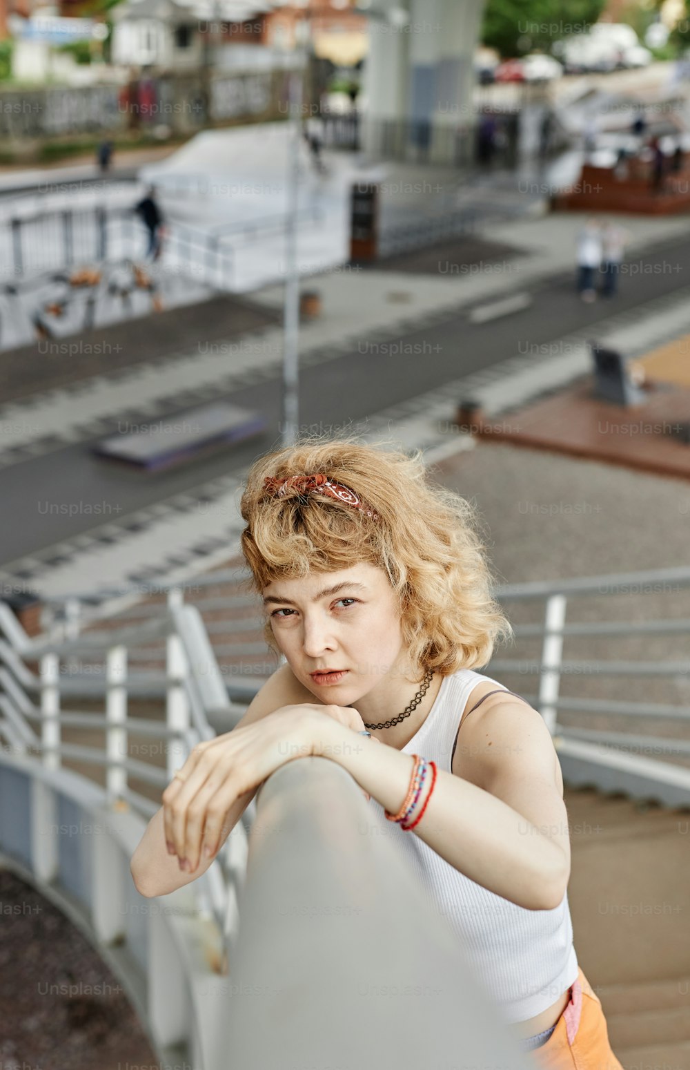Vertikales Porträt einer echten jungen Frau, die im Freien in die Kamera schaut, während sie auf einer Metalltreppe posiert