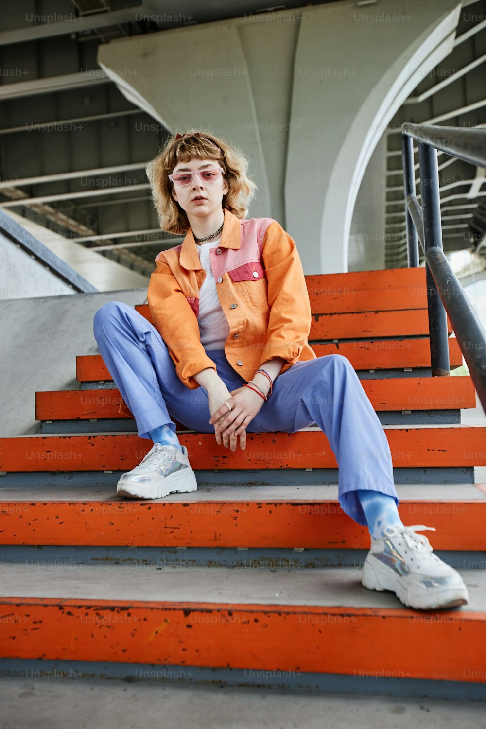 Retrato vertical da mulher despreocupada jovem que veste a moda colorida do estilo de rua ao ar livre no ambiente urbano