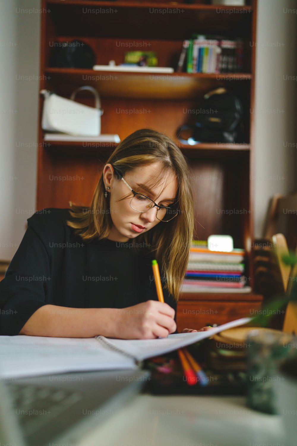Una joven estudiante caucásica sentada en casa escribiendo en su cuaderno sosteniendo un lápiz mientras estudia preparándose para el examen concepto de aprendizaje y educación personas reales copian espacio