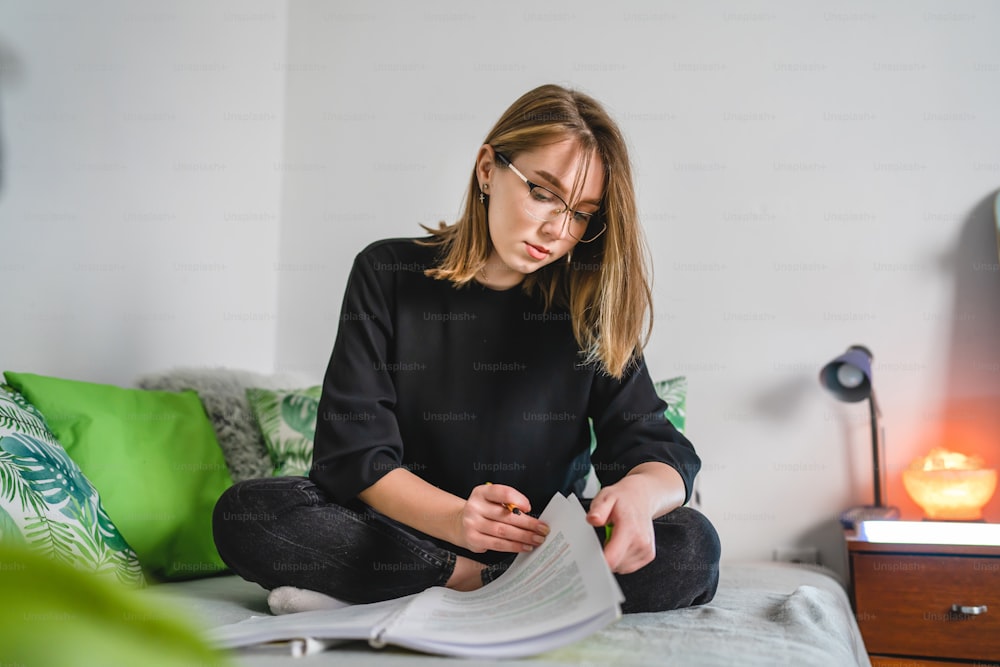 One young caucasian woman female student study while lying in her bed at home