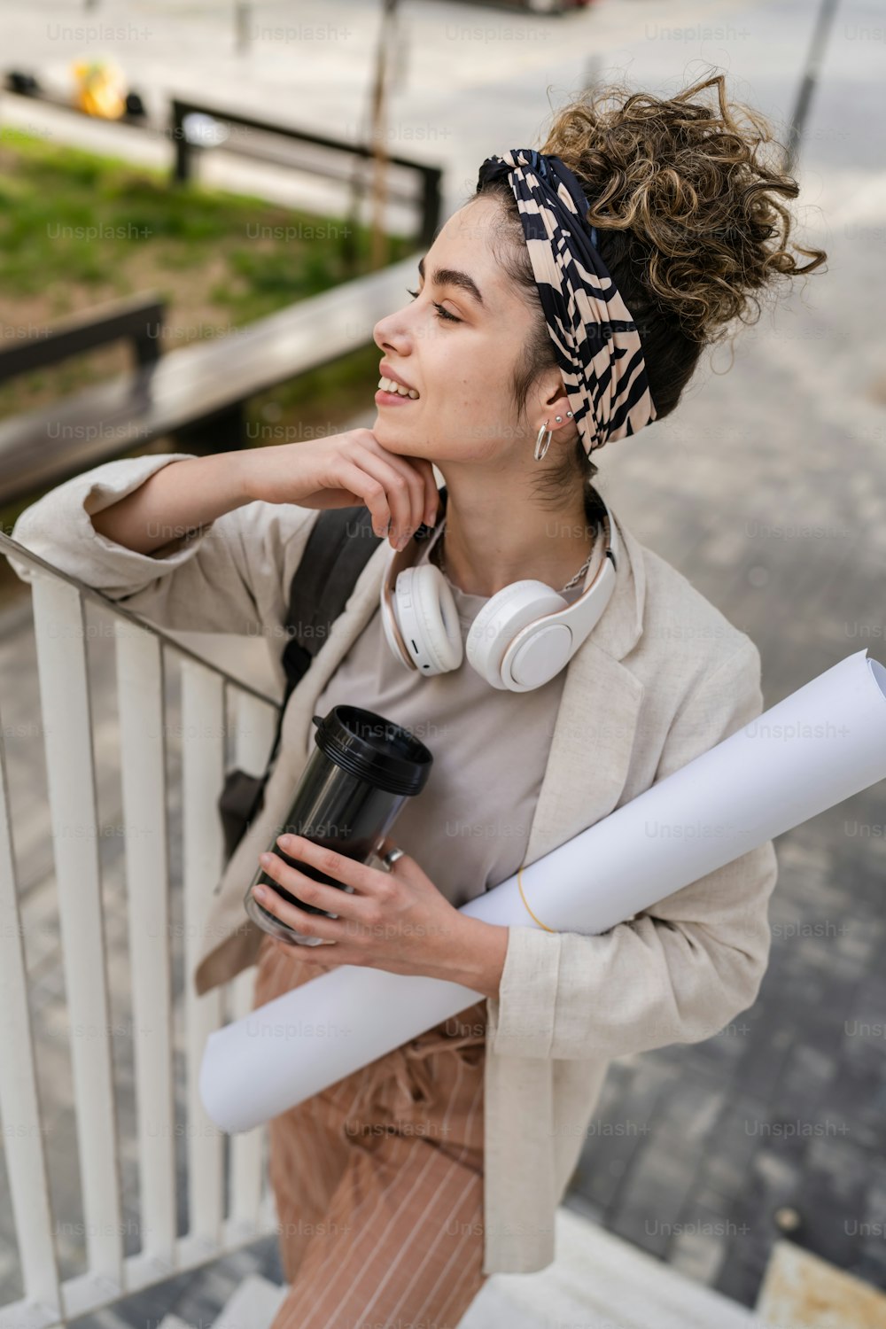 One woman young adult caucasian female student with backpack standing or walking in front of university building with paper and cup of coffee outdoor in bright day happy smile real people copy space