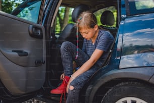 차에 앉아 빨간 운동화를 신고 있는 어린 소녀