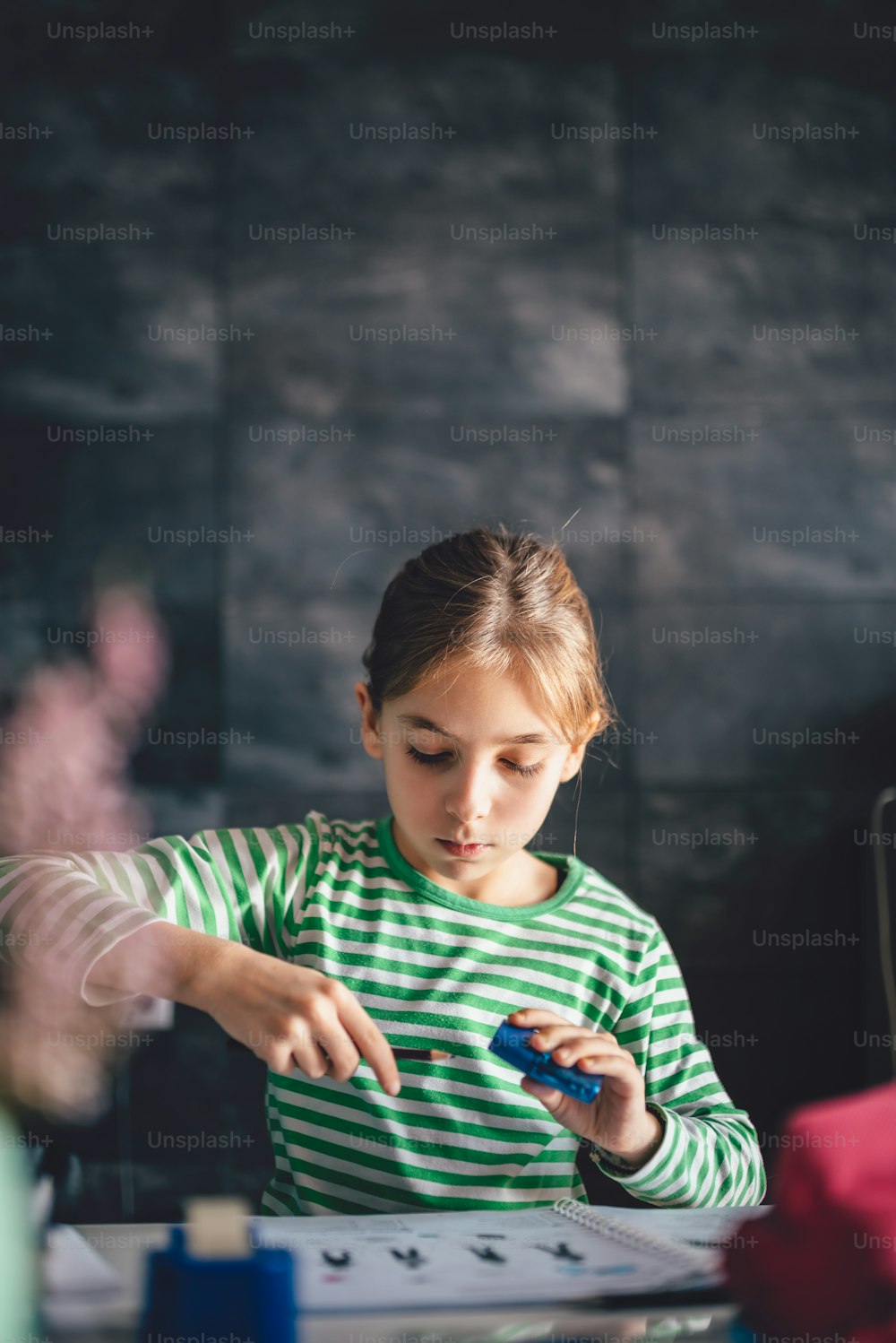 Girl doing homework in living room and sharpening the pencil