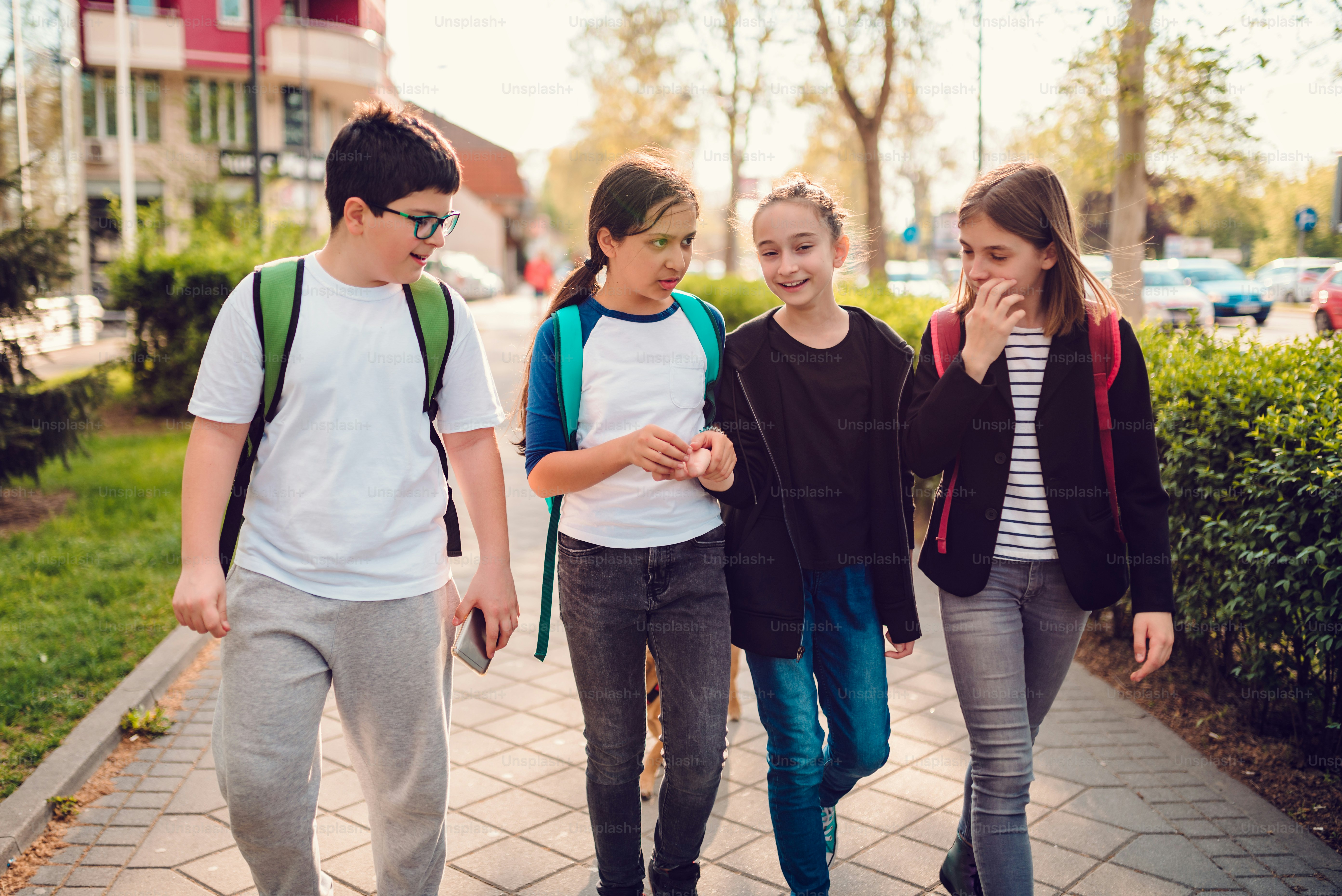Group of schoolmates going home after school on sunny day and having fun