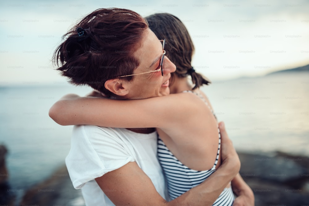 Madre e hija abrazándose en la playa junto al mar