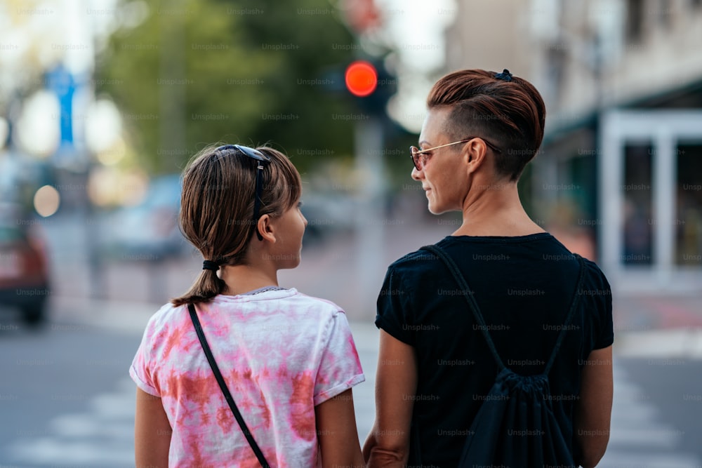 Mother and daughter waiting for green light to cross the street while looking each other