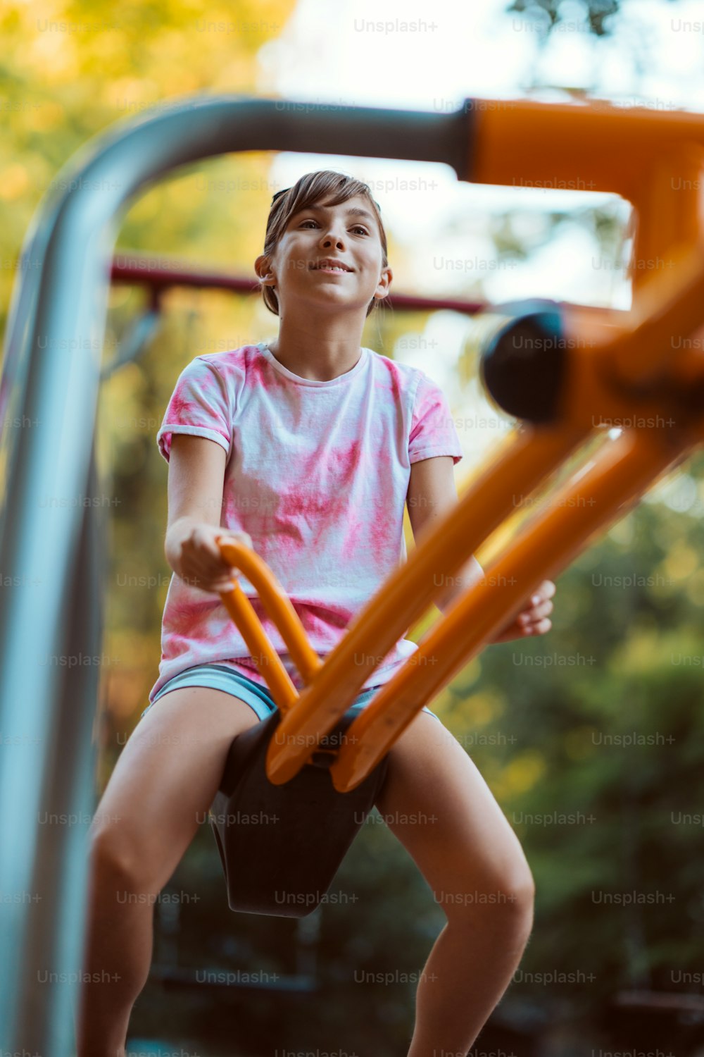 Menina feliz que joga ao ar livre no playground em uma gangorra