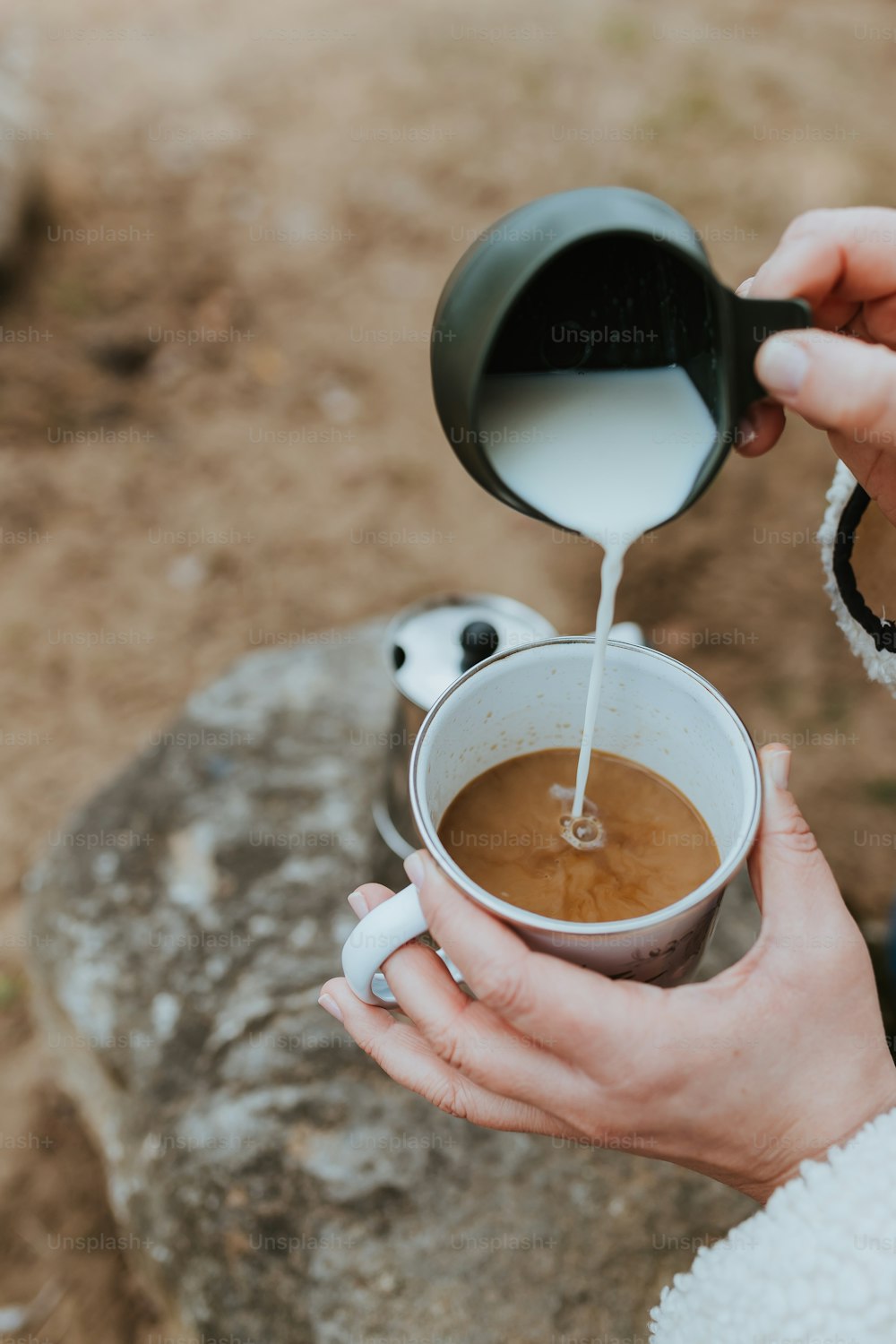 a person pouring milk into a cup of coffee