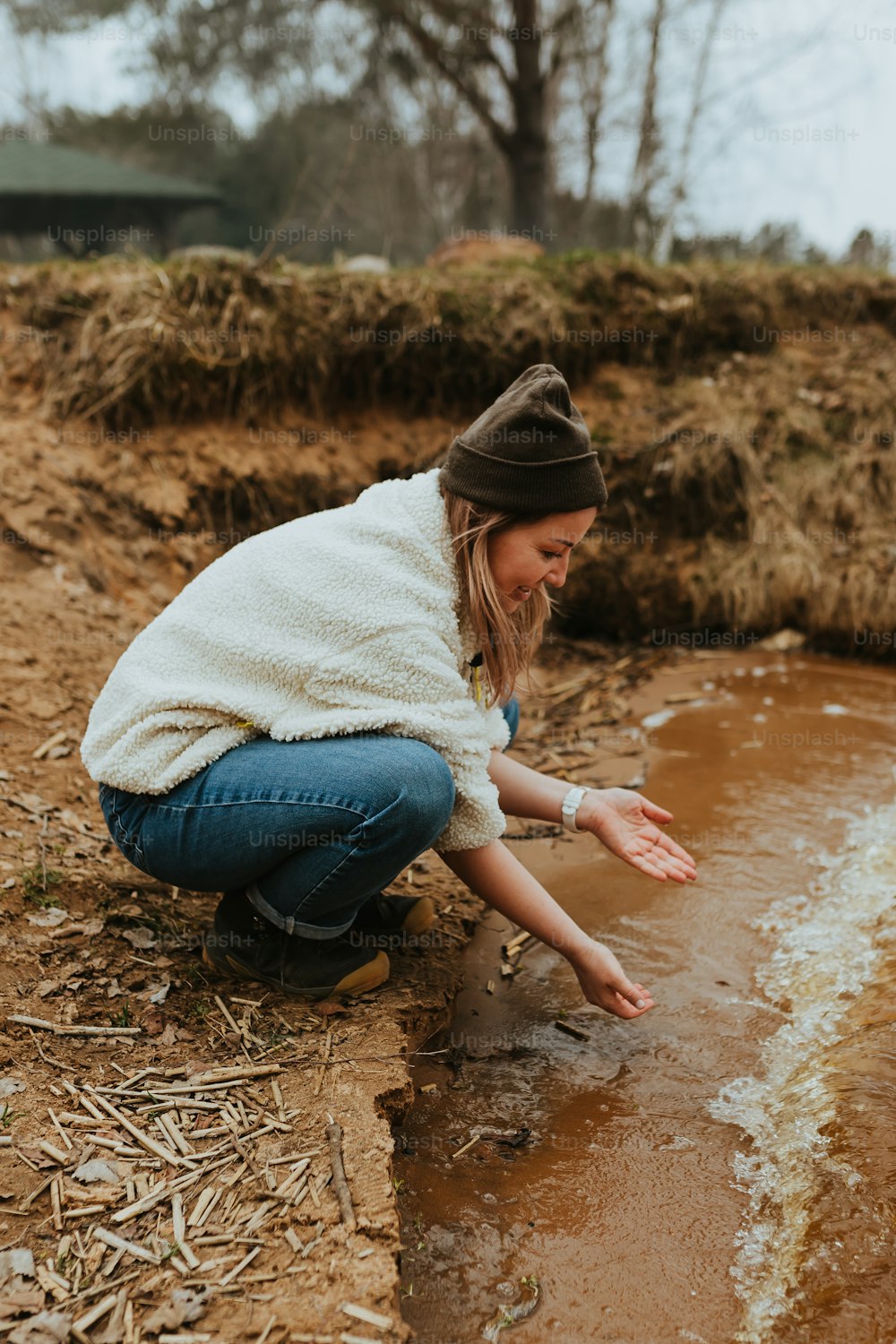 a woman kneeling down next to a puddle of water