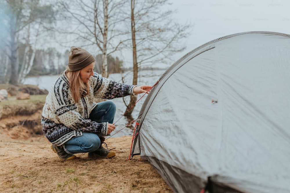 a woman setting up a tent in the woods