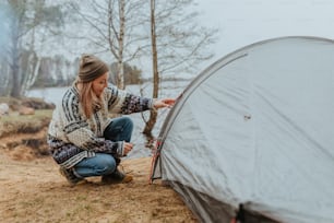 Une femme installant une tente dans les bois
