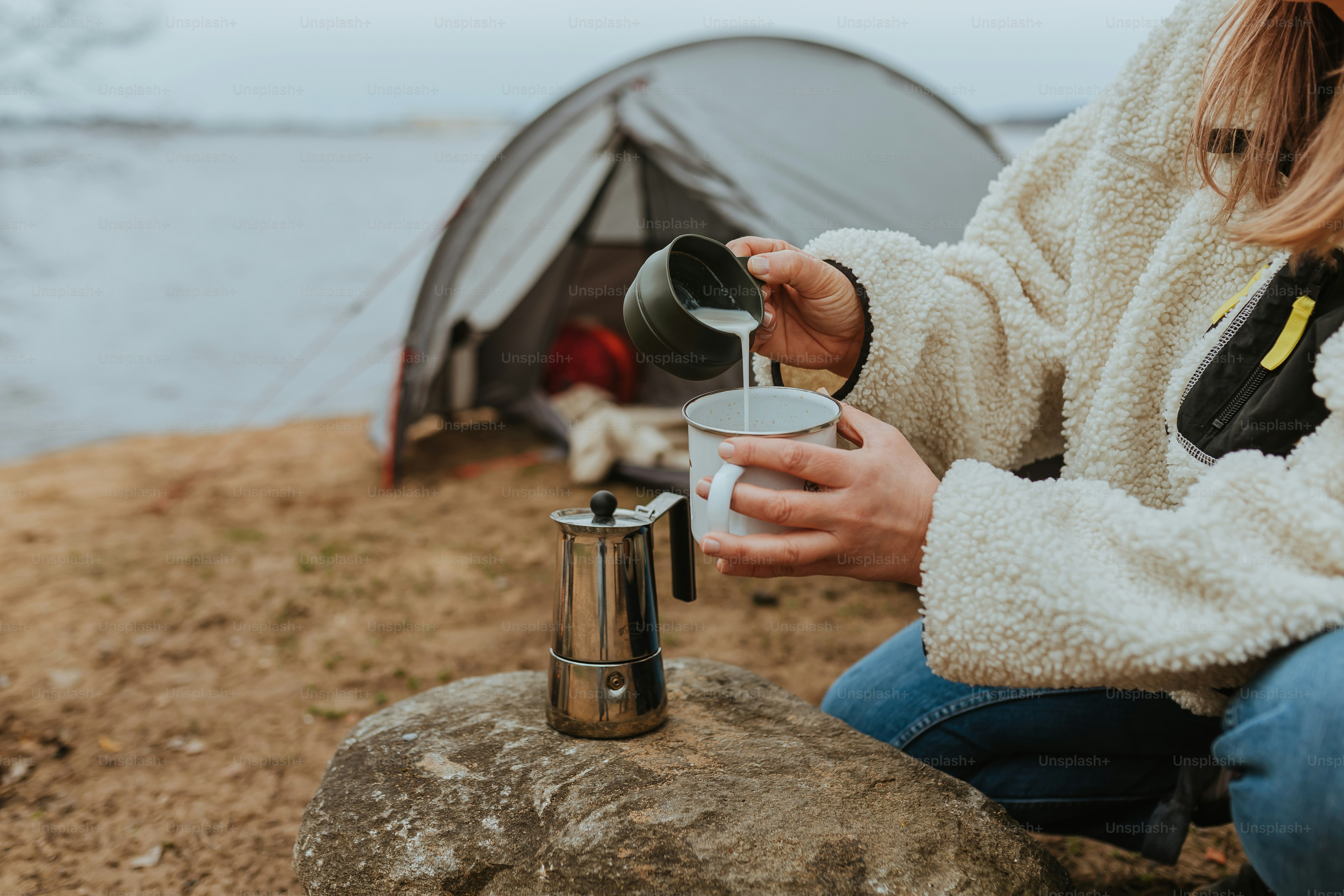 a woman sitting on a rock next to a tent