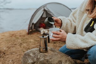 a woman sitting on a rock next to a tent