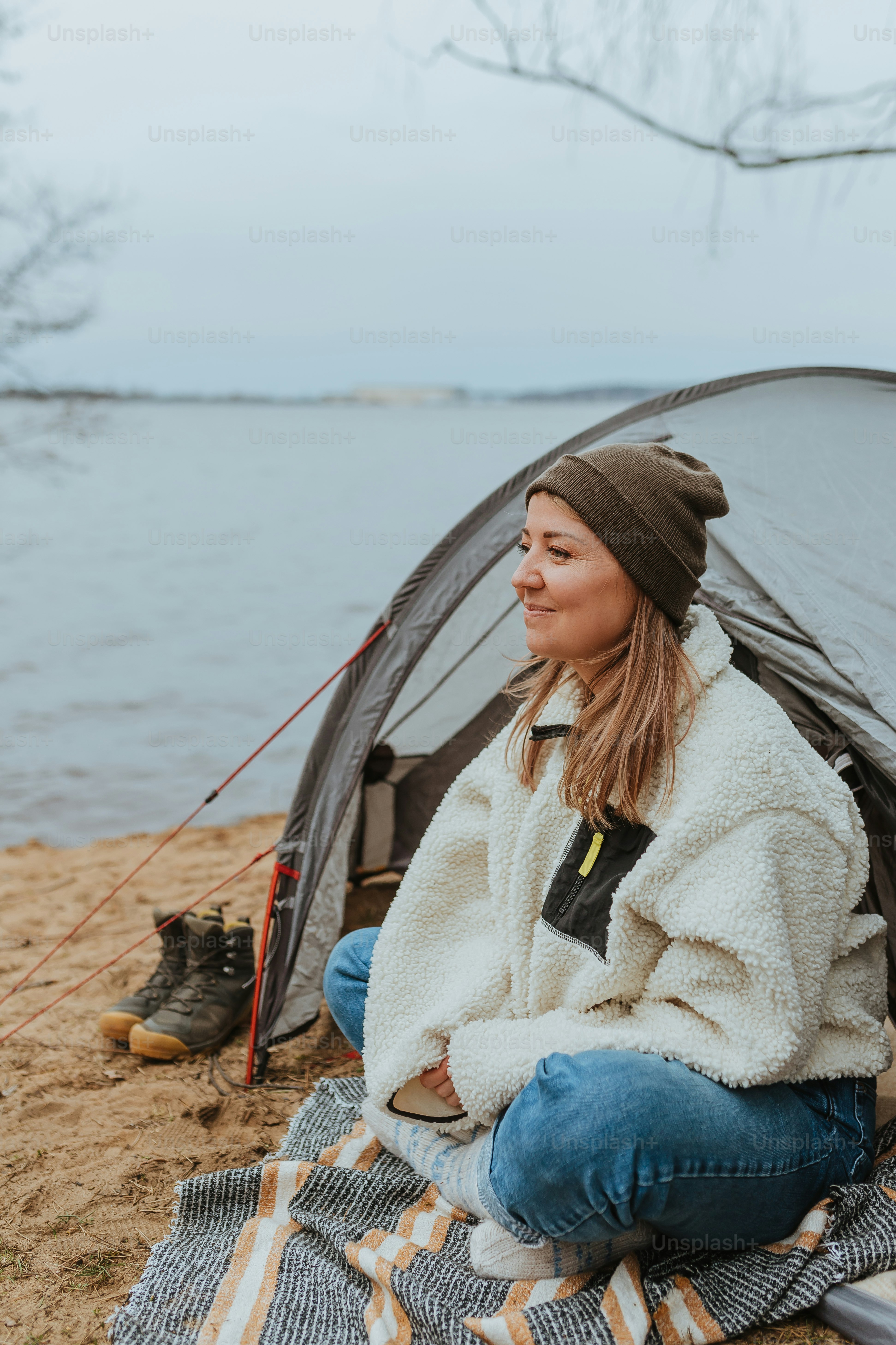 A woman sitting in a tent next to a lake photo – Campfire Image on Unsplash